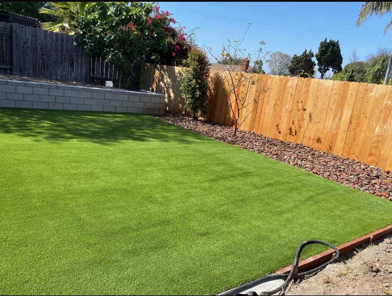 Backyard artificial turf with cedar fence and rock border