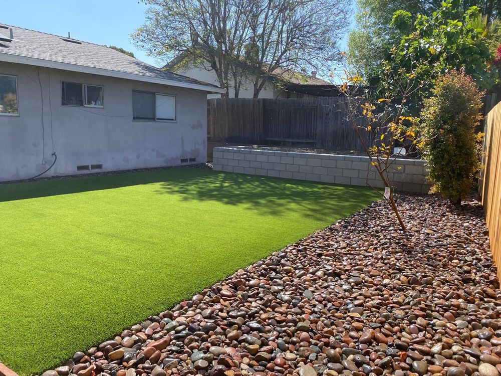 Backyard after — artificial turf with river rock border