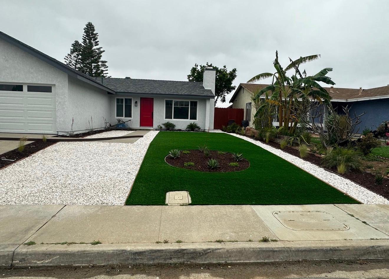 Front yard after — artificial turf, white rock and garden bed