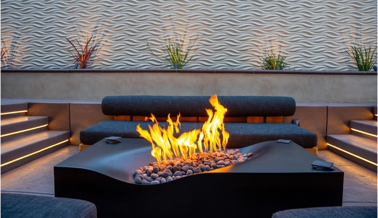Luxury outdoor fire pit lounge with decorative wave wall and step lighting