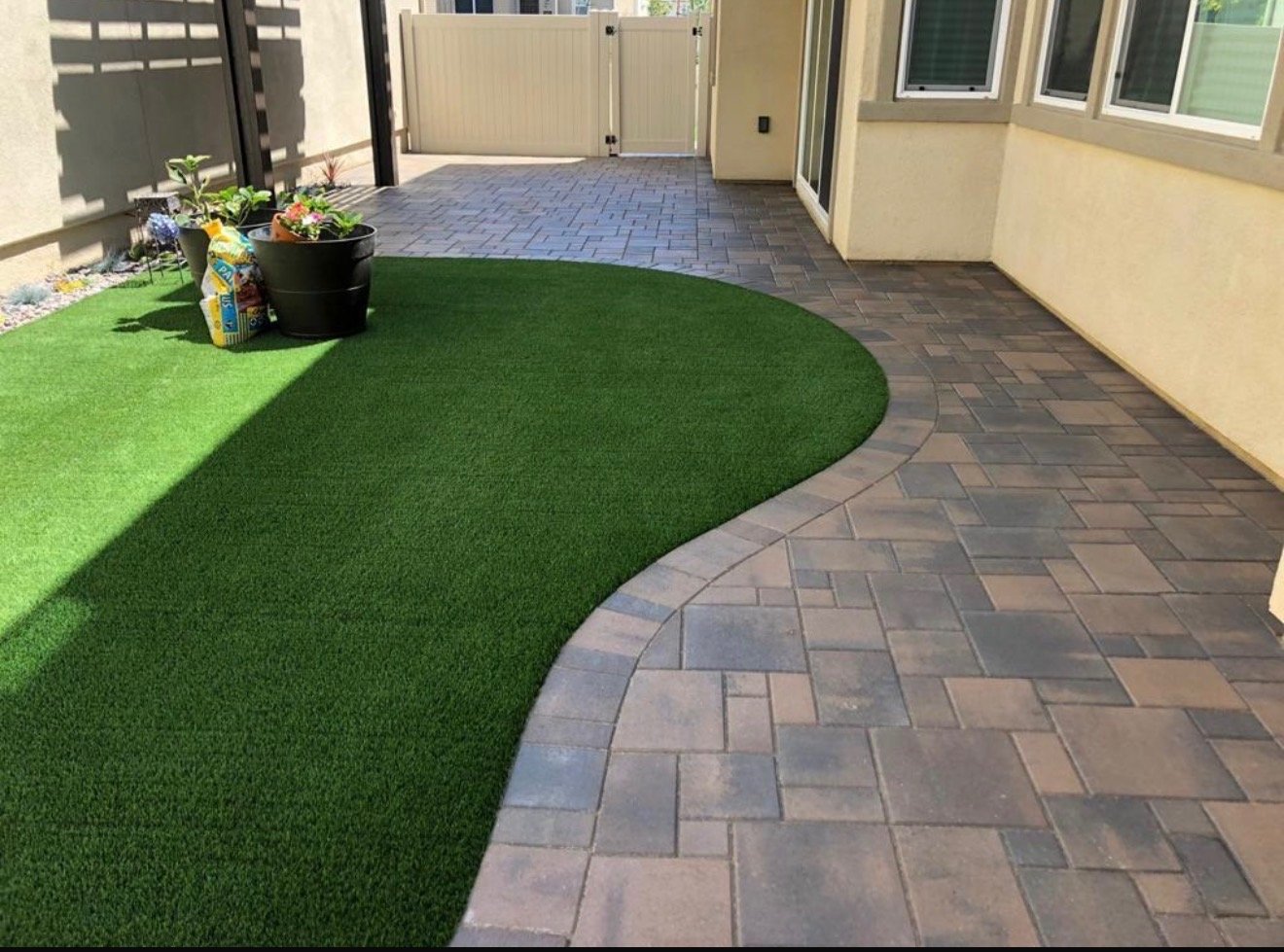 Side yard with curved artificial turf and paver path