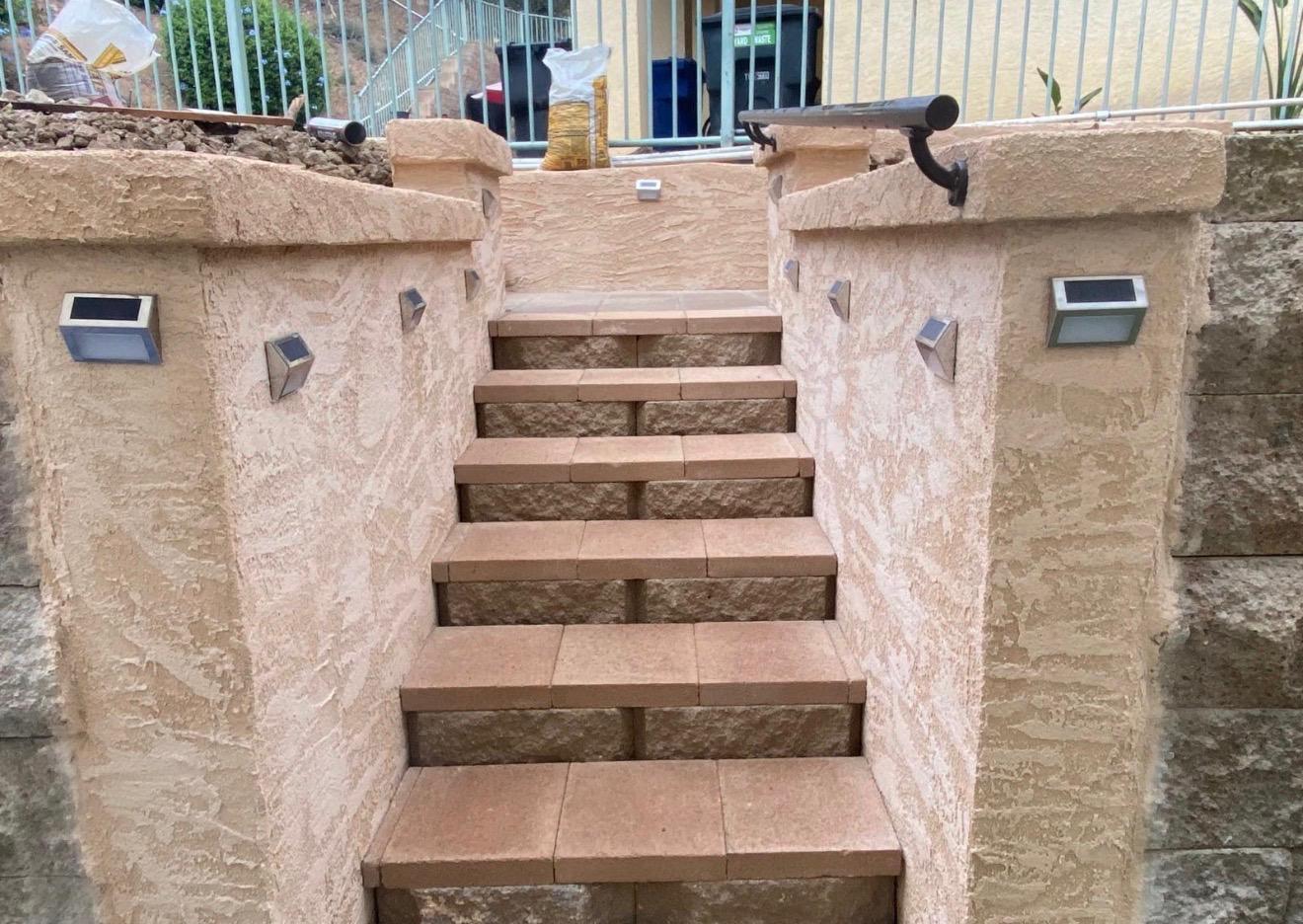Staircase after — finished stucco entry staircase with tile treads and solar lights